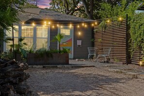 A house with a patio area, string lights, a wooden fence, and outdoor seating. - East Austin Studio | Near UT, Downtown & Mueller (Austin)