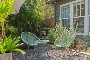 A patio with two green chairs, a small table, and a variety of plants. - East Austin Studio | Near UT, Downtown & Mueller (Austin)