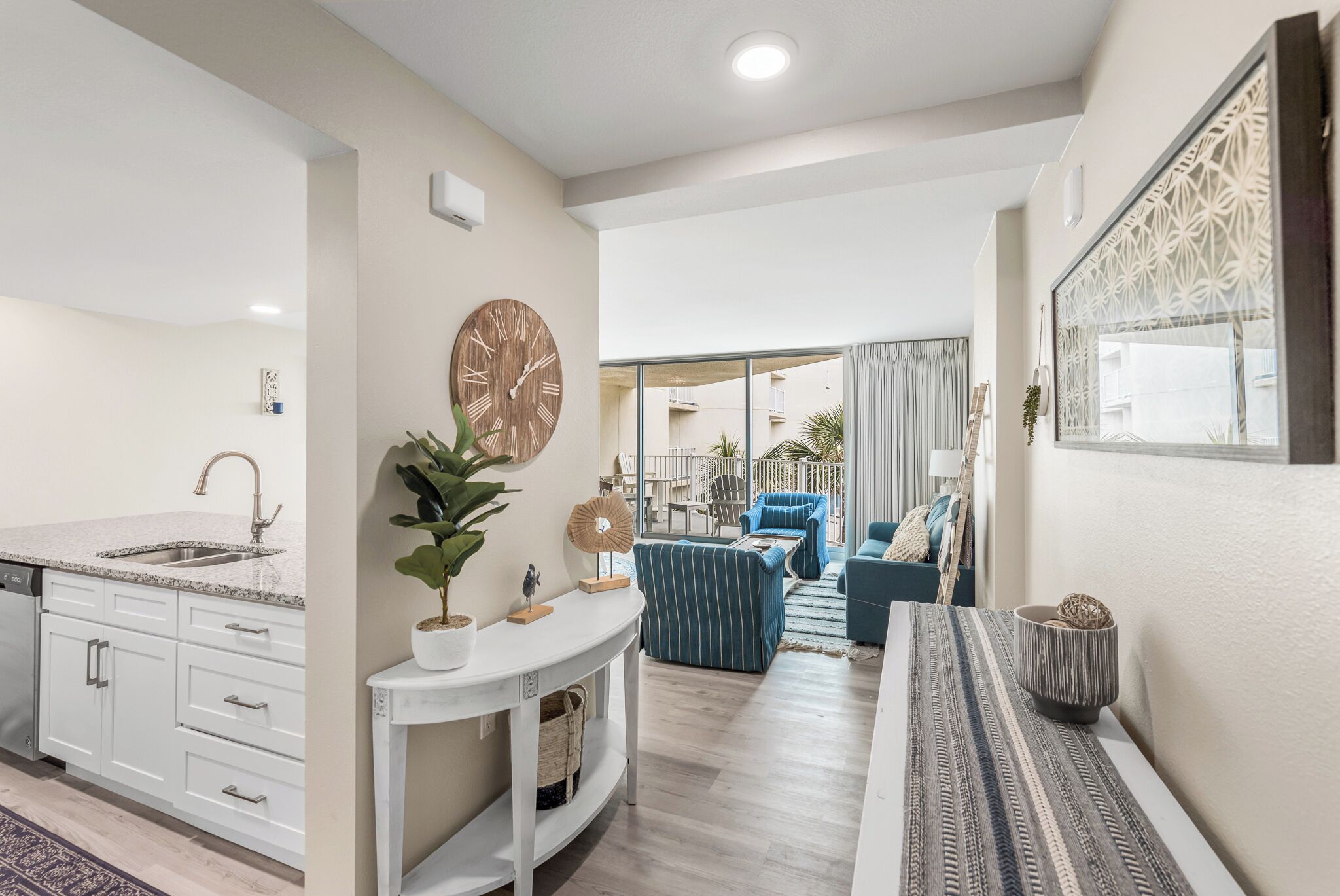 A modern kitchen with a built-in dishwasher, a white countertop, and a wall-mounted clock.