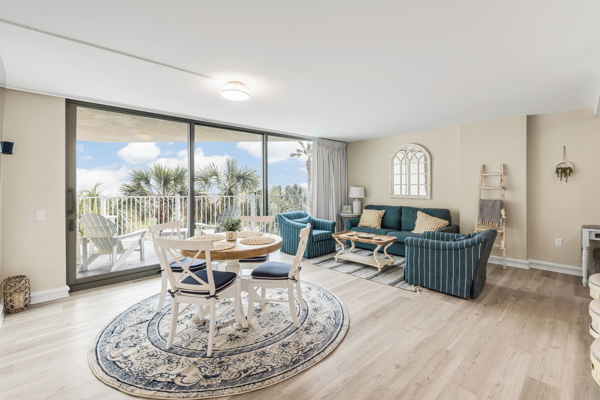 Ein geräumiges Wohnzimmer mit einer großen Schiebetür zum Balkon, einem runden Esstisch mit Stühlen, einer Couch und einem Couchtisch.