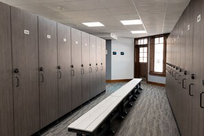 A row of lockers with numbers, a long bench, and a window with natural light. - Crystal Peak Lodge (Breckenridge)
