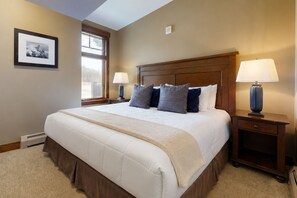 A hotel room with a large bed, two bedside lamps, a framed picture on the wall, and a window with blinds. - Crystal Peak Lodge (Breckenridge)