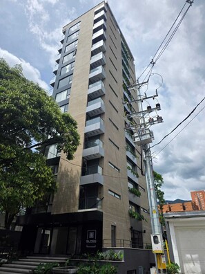 A multi-story building with a modern architectural design, featuring a prominent entrance with a glass facade and a sign that reads 'BLOSS.'