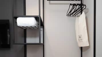 A modern, compact hotel room with a bunk bed, a desk with a coffee maker, and a small seating area.