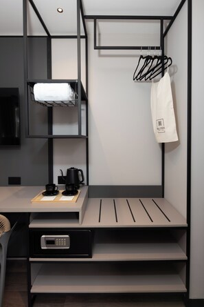 Habitación de hotel moderna y compacta con literas, un escritorio con cafetera y una pequeña zona de estar.