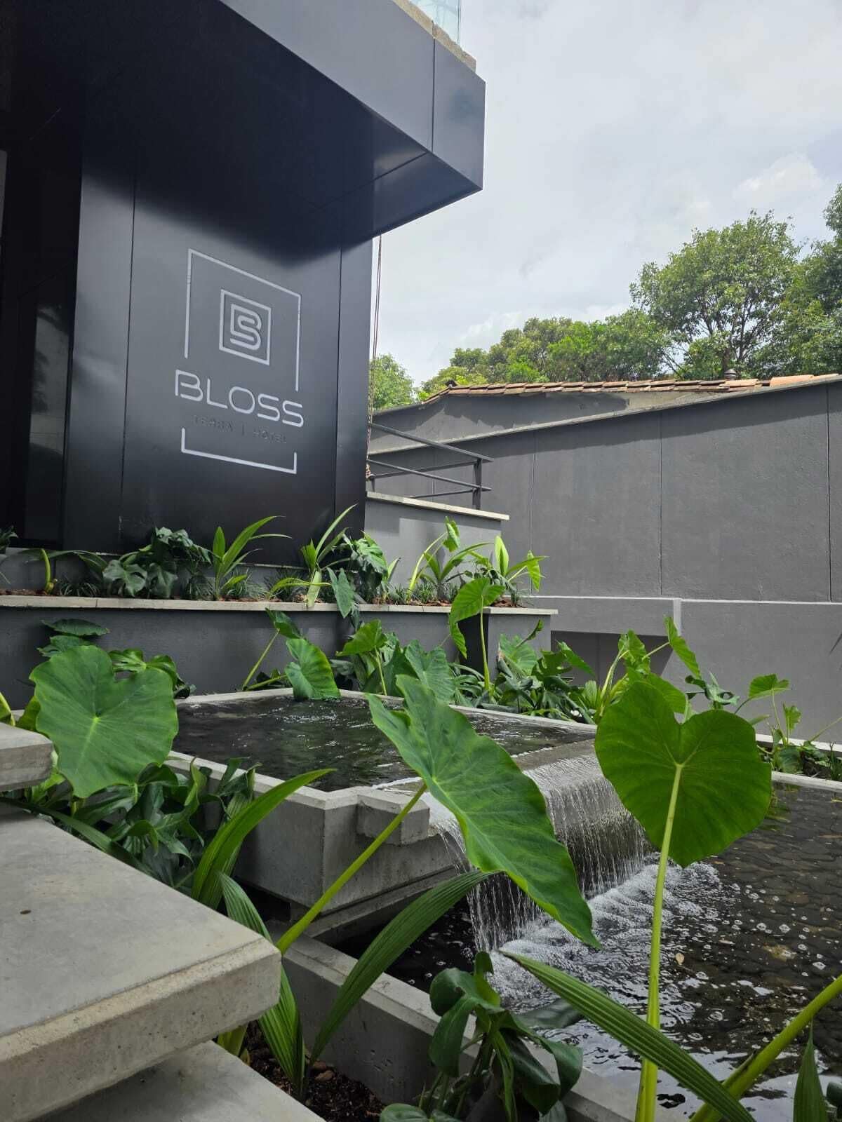 A modern building with a water feature and lush greenery.
