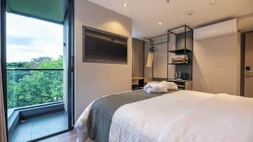 Una habitación de hotel moderna con una cama grande, un armario, un área de descanso y vistas a zonas verdes.