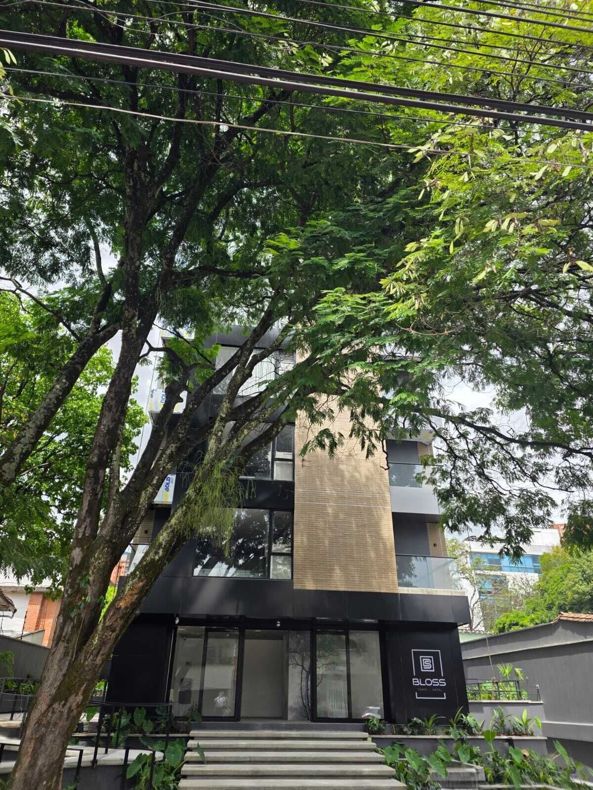 Un edificio moderno con fachada de vidrio, una estructura vertical destacada y una escalera que lleva a la entrada.