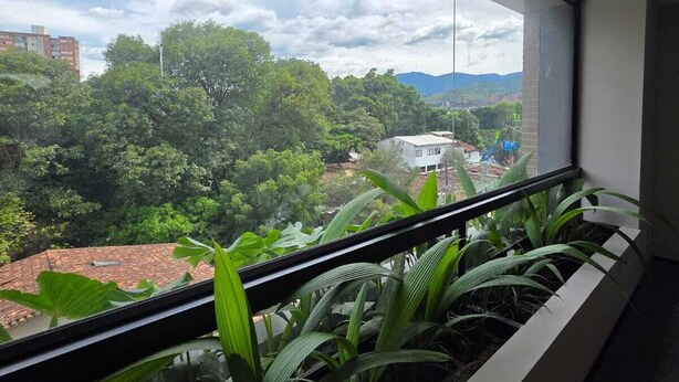 A balcony with a view of a cityscape and greenery.