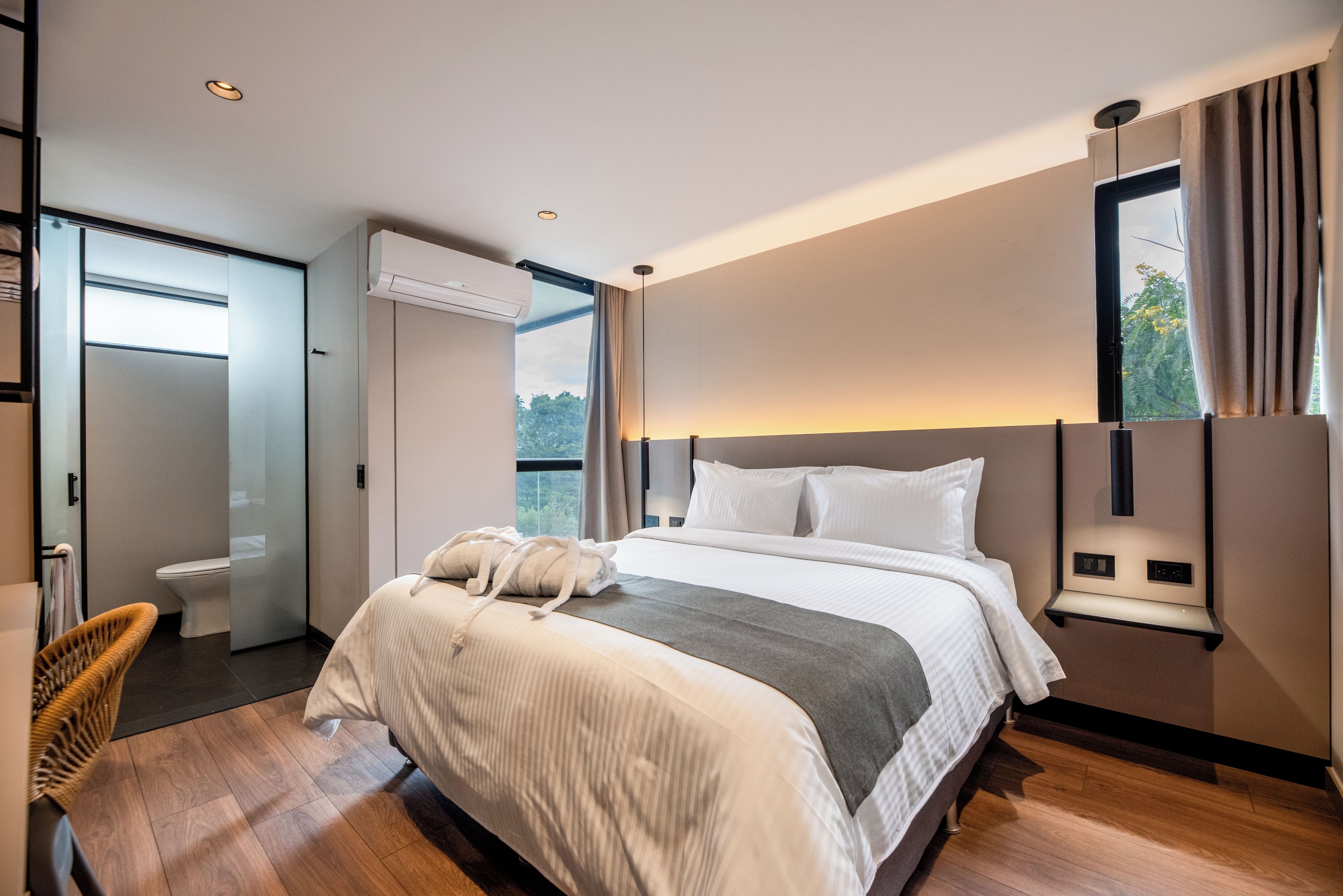 Een moderne hotelkamer met een groot bed, een nachtkastje, een stoel en een raam met gordijnen.