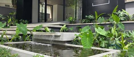 A modern building with a sign reading 'BLOSS HOTEL' and a small water feature in the foreground.