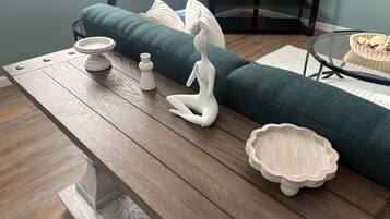 A modern living room with a wooden coffee table, a green sofa, and decorative items including a white ceramic sculpture and a small wooden bowl.