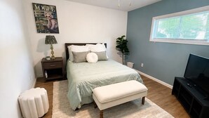 Ein Schlafzimmer mit einem Bett, einem Nachttisch, einer Lampe und einem Fernseher.