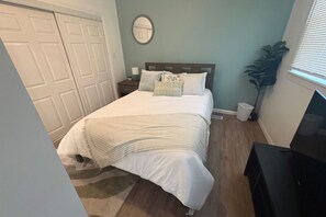 Une chambre à coucher avec un lit, une table de chevet, une lampe et une plante en pot.