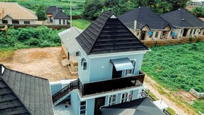 A multi-story residential building with a black roof, a balcony on the second floor, and a visible driveway. - The Haven | Modern 2BR En-suite Flat (Ibadan)
