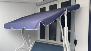 A waiting area with a blue bench and a canopy, a window, and a sign reading 'TITILOPE'S APARTMENT'. - The Haven | Modern 2BR En-suite Flat (Ibadan)