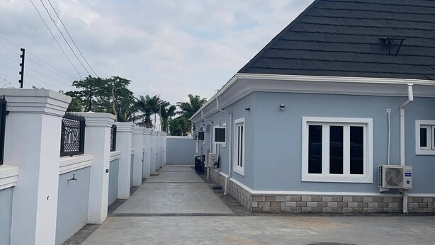 A residential building with a grey roof, white walls, and a paved driveway. - The Haven | Modern 2BR En-suite Flat (Ibadan)