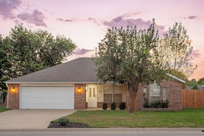A single-story house with a garage, a front door, and a small front yard. - Quiet 3-Bedroom Home Convenient to Everything Northwest Arkansas has to Offer (Centerton)