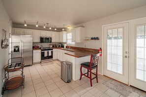 A modern kitchen with white cabinetry, stainless steel appliances, and a wooden island. - Quiet 3-Bedroom Home Convenient to Everything Northwest Arkansas has to Offer (Centerton)