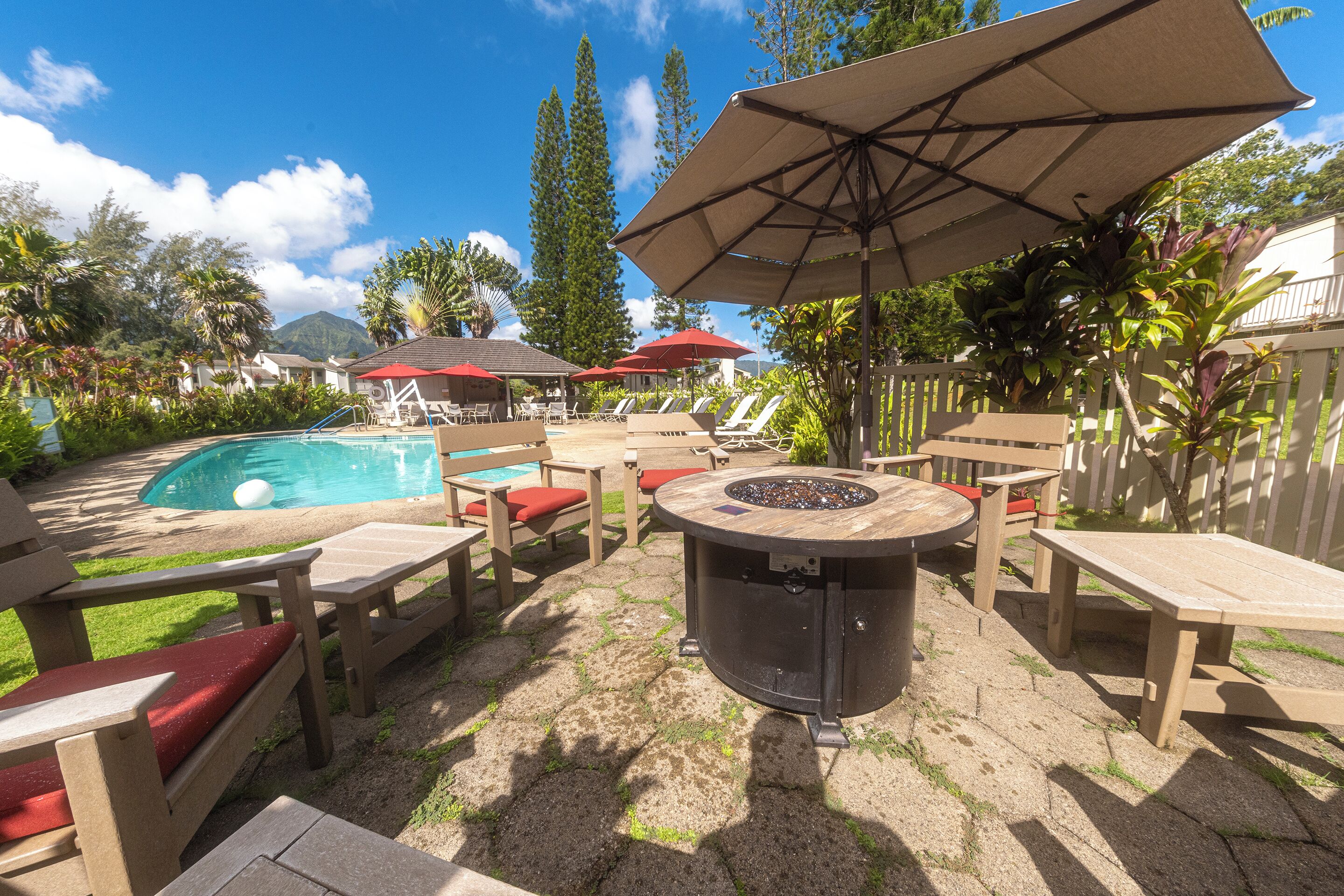 An outdoor patio area with a pool, lounge chairs, and a fire pit.
