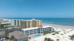 A beachfront hotel with a swimming pool, multiple balconies, and a view of the ocean. - Sun and Sand Getaway @ Coastal Waters (New Smyrna Beach)