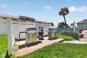 A patio area with outdoor grills and a sign instructing to clean the grill after use. - Sun and Sand Getaway @ Coastal Waters (New Smyrna Beach)