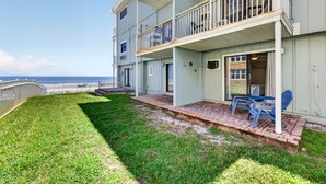 A multi-story building with a balcony, a grassy lawn, and a view of the ocean. - Sun and Sand Getaway @ Coastal Waters (New Smyrna Beach)