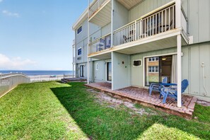 A multi-story building with a balcony, a grassy lawn, and a view of the ocean. - Sun and Sand Getaway @ Coastal Waters (New Smyrna Beach)
