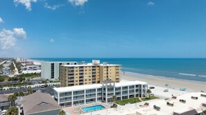 A beachfront hotel with a pool, multiple balconies, and a view of the ocean. - Sun and Sand Getaway @ Coastal Waters (New Smyrna Beach)