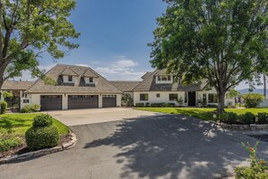 A two-story house with a driveway, garage, and well-maintained lawn. - Chateau Blanc Vineyard Estate w/ 7 bedrooms, 5.5 bathrooms, pool, spa, fire pit (Temecula)