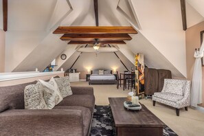 A cozy attic bedroom with a bed, a sofa, a chair, and a dining table. - Chateau Blanc Vineyard Estate w/ 7 bedrooms, 5.5 bathrooms, pool, spa, fire pit (Temecula)