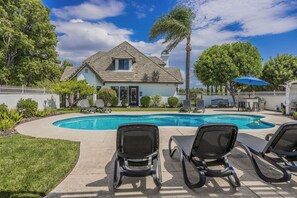 A residential property with a swimming pool, two lounge chairs, a white fence, and a house with a gabled roof. - Chateau Blanc Vineyard Estate w/ 7 bedrooms, 5.5 bathrooms, pool, spa, fire pit (Temecula)