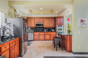 A kitchen with wooden cabinets, stainless steel appliances, and a tiled floor. - Chateau Blanc Vineyard Estate w/ 7 bedrooms, 5.5 bathrooms, pool, spa, fire pit (Temecula)