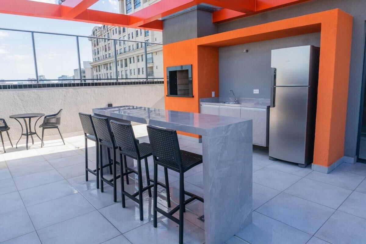 Una terraza en la azotea con zona de bar, asientos y un refrigerador.