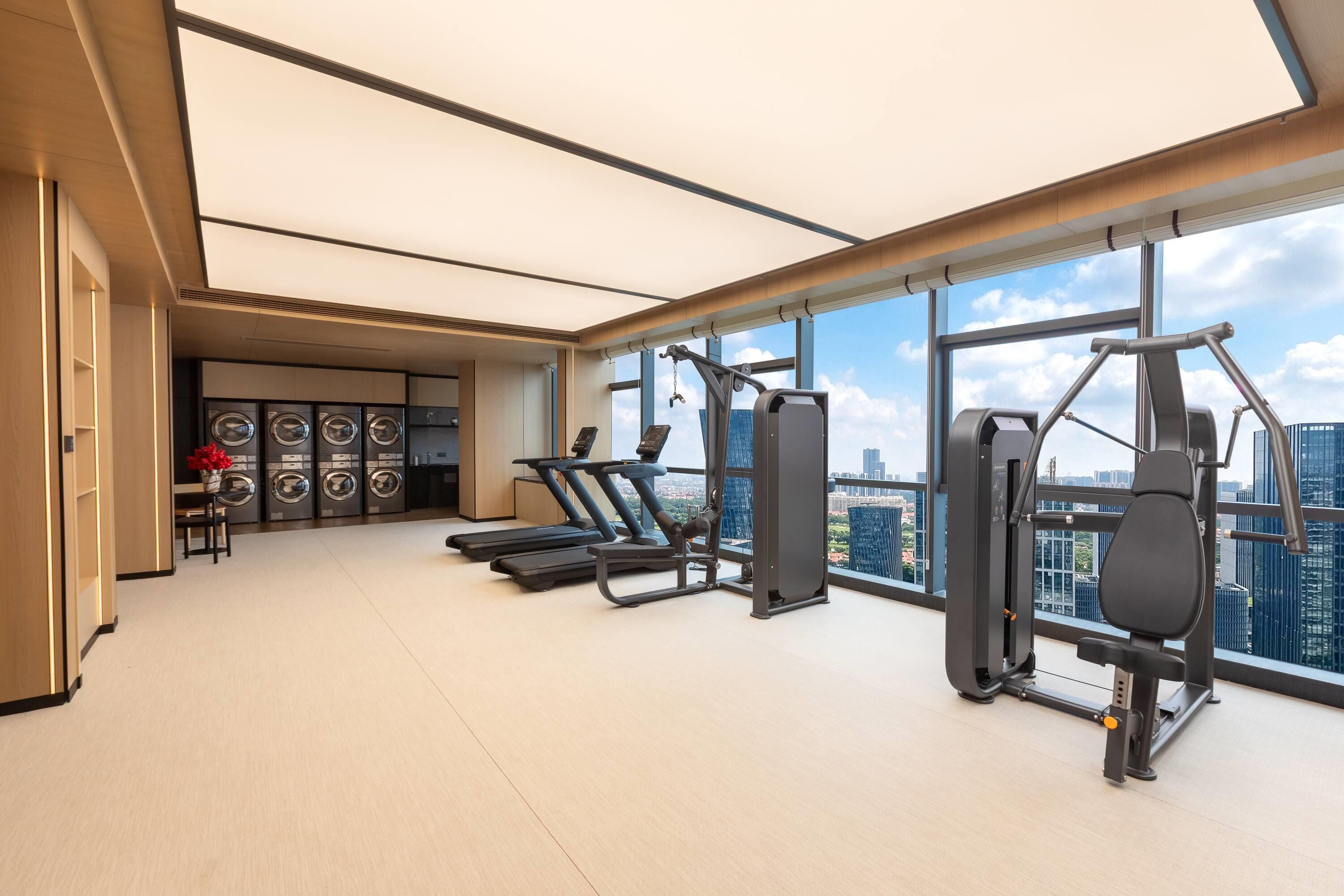 A modern gym with exercise equipment and a view of the cityscape.