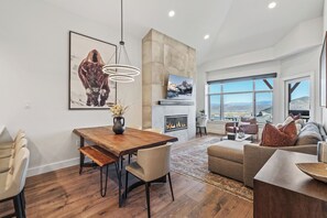 Una sala de estar moderna con chimenea, un comedor y un ventanal con vistas a la montaña.