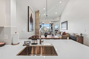 Una cocina moderna con un lavamanos de acero inoxidable, una mesa de comedor de madera y un ventanal con vistas a la ciudad.