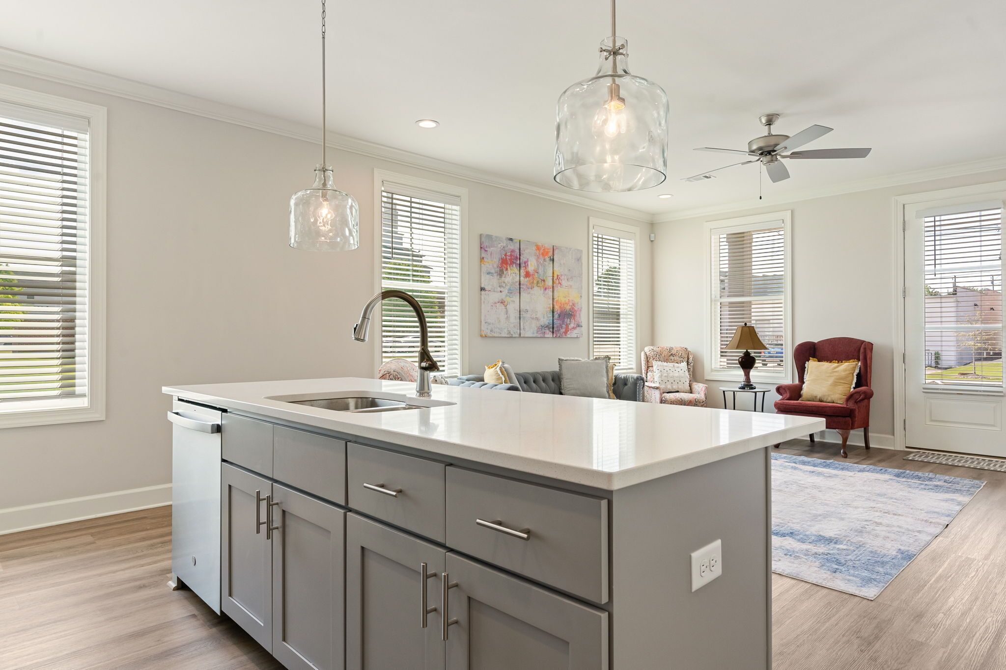 A modern kitchen with a large island, stainless steel appliances, and pendant lighting.