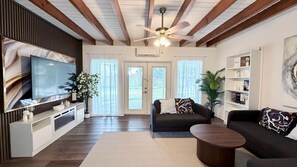 A living room with a flat-screen TV, a sofa, a coffee table, and a ceiling fan. - S. Tampa Retreat w/ Chef Kitchen (Tampa)