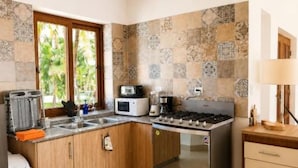 Una cocina con gabinetes de madera, una estufa de acero inoxidable y un ventanal con vistas a palmeras.