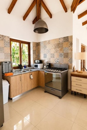 A kitchen with wooden cabinets, a stainless steel stove, and a window with a view of palm trees.