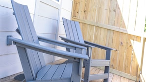 Two grey Adirondack chairs on a wooden deck.