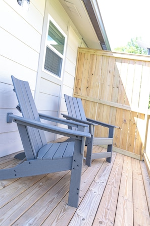 Two grey Adirondack chairs on a wooden deck.