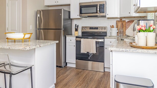 A modern kitchen with stainless steel appliances, a wooden island, and a bar stool.