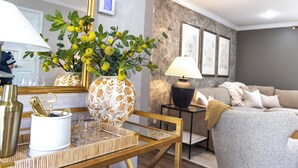 A living room with a sofa, a coffee table with decorative items, a lamp, and a wall-mounted thermostat.