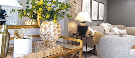Sala de estar com sofá, mesa de centro com objetos decorativos, luminária e termostato fixado na parede.