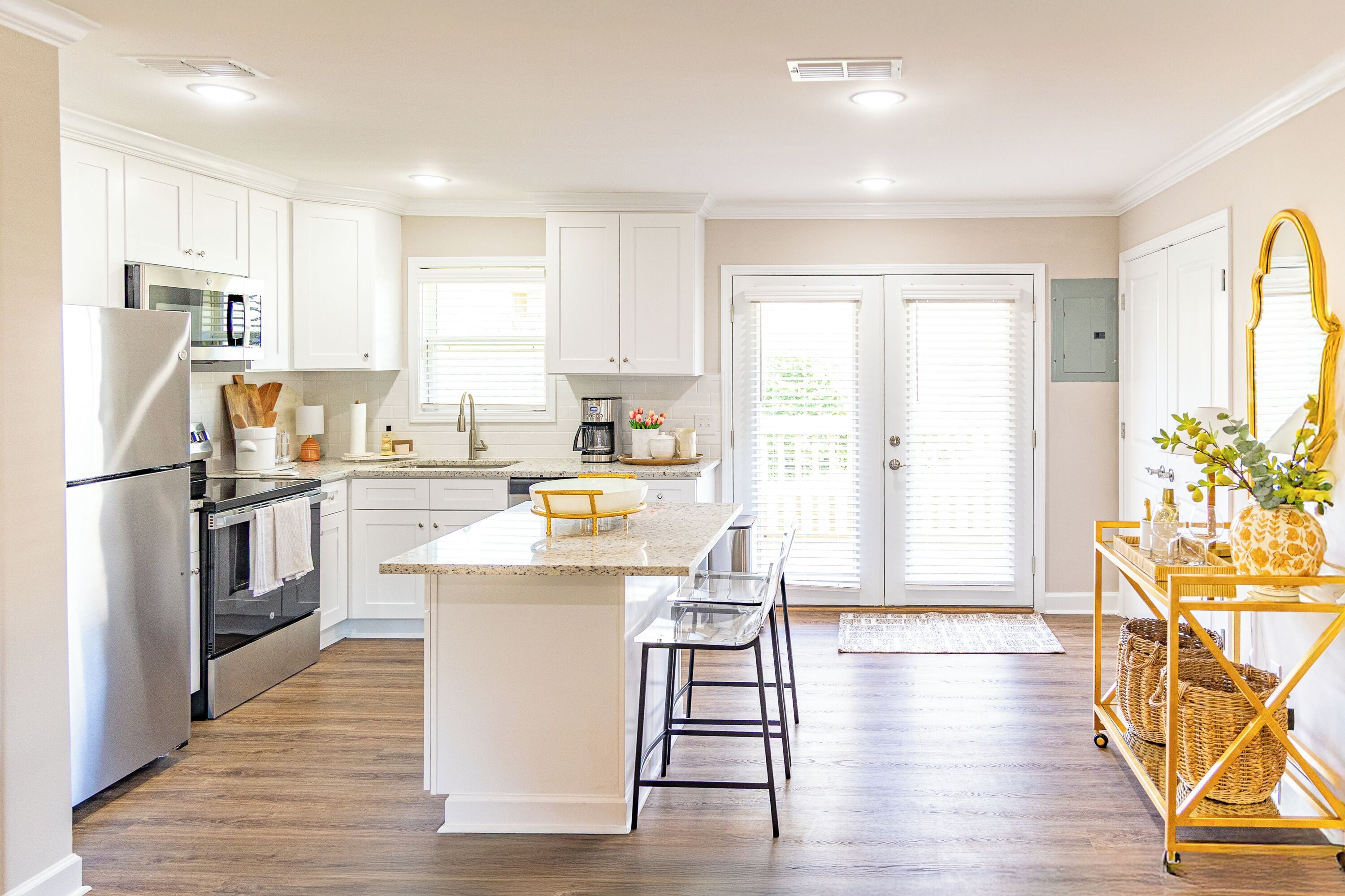 A modern kitchen with white cabinetry, stainless steel appliances, and a central island with bar stools.