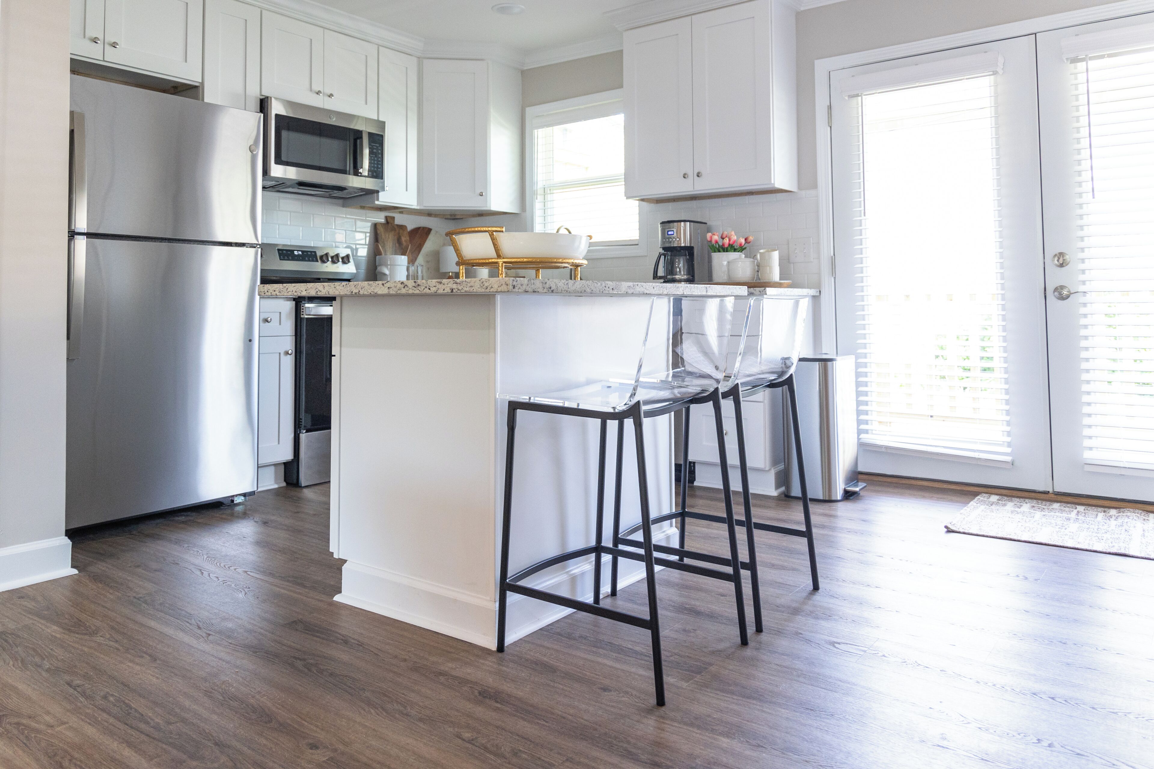 A modern kitchen with stainless steel appliances, white cabinetry, and a central island with bar stools.