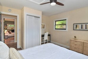 Ein Schlafzimmer mit Bett, Schreibtisch, Stuhl, Kleiderschrank und Deckenventilator.