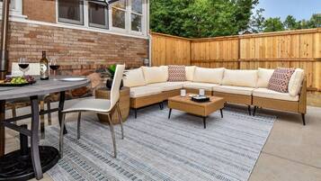 En udendørs terrasse med spisebord, stole, en sofa og et sofabord.